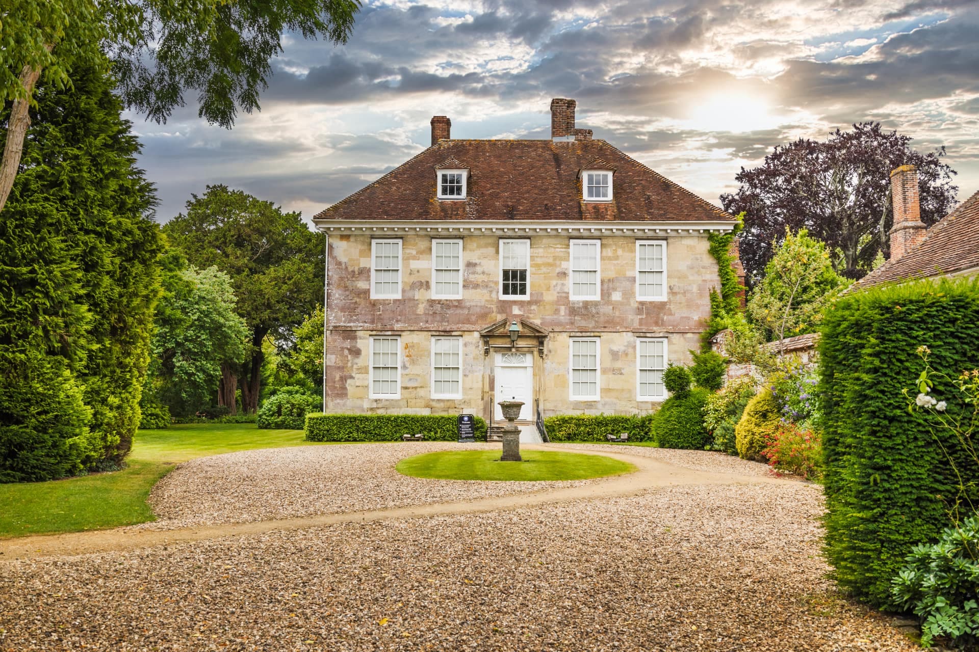 A Georgian country house in the West Kent countryside, sash windows above a gravel carriage drive.